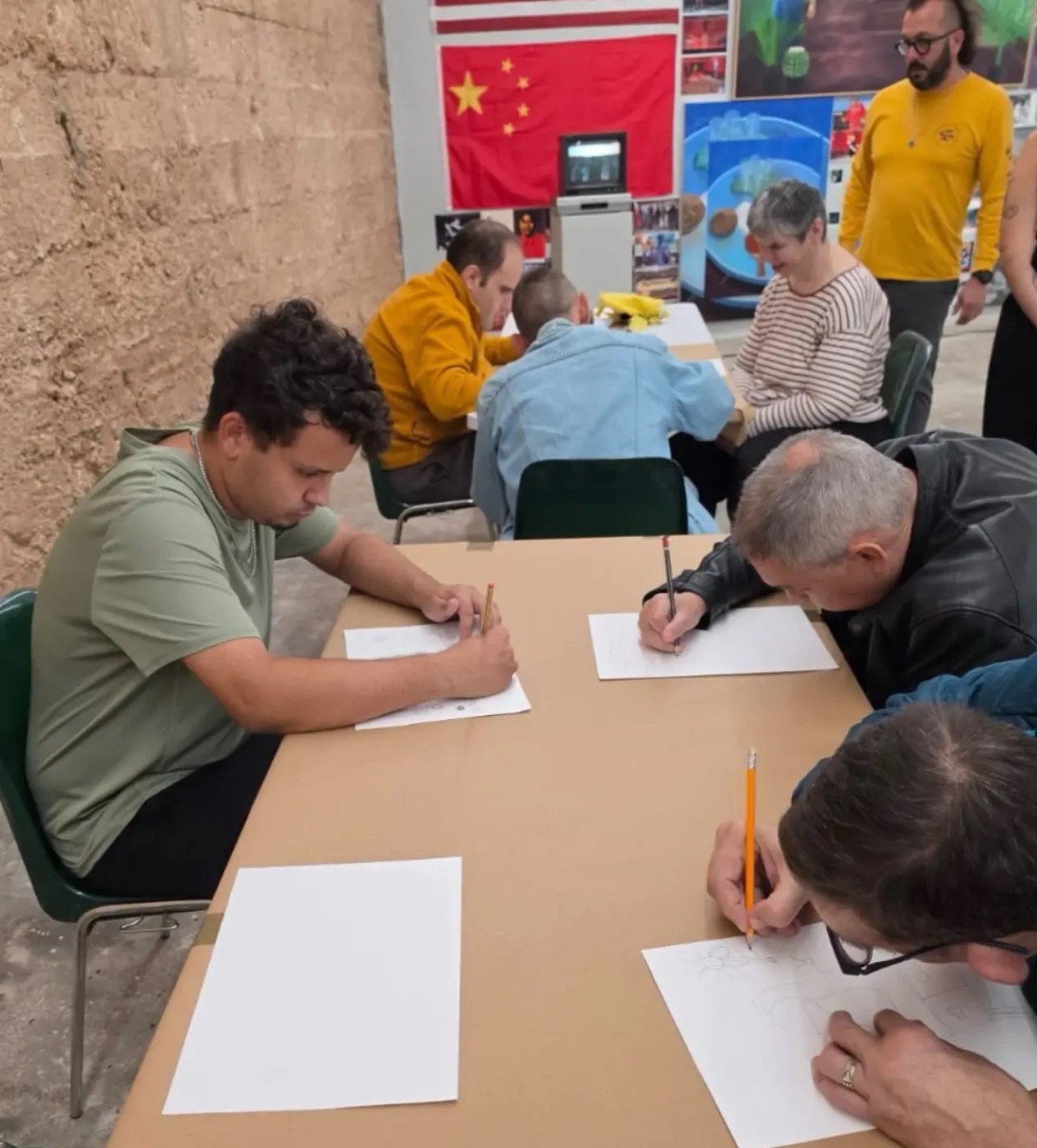 Artistes dibuixant a la taula durant un taller
